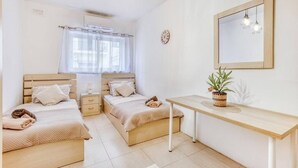 Un dormitorio con dos camas, una mesita de noche, un espejo y una planta en maceta.