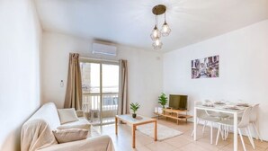 Una sala de estar moderna con sofá, mesa de centro, televisor y zona de comedor.