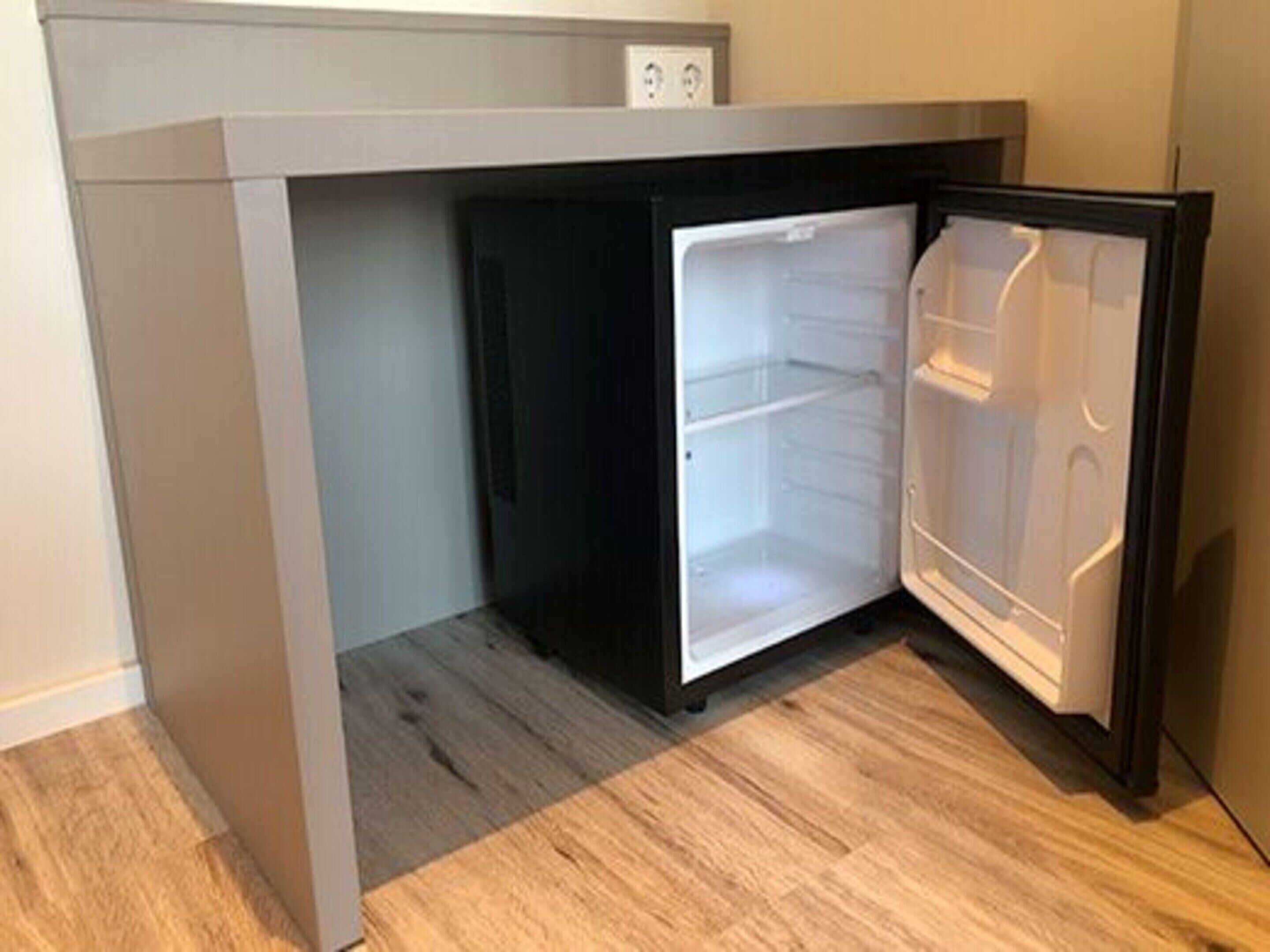 Un petit réfrigérateur encastrable à une seule porte, placé sous un plan de travail dans une cuisine.