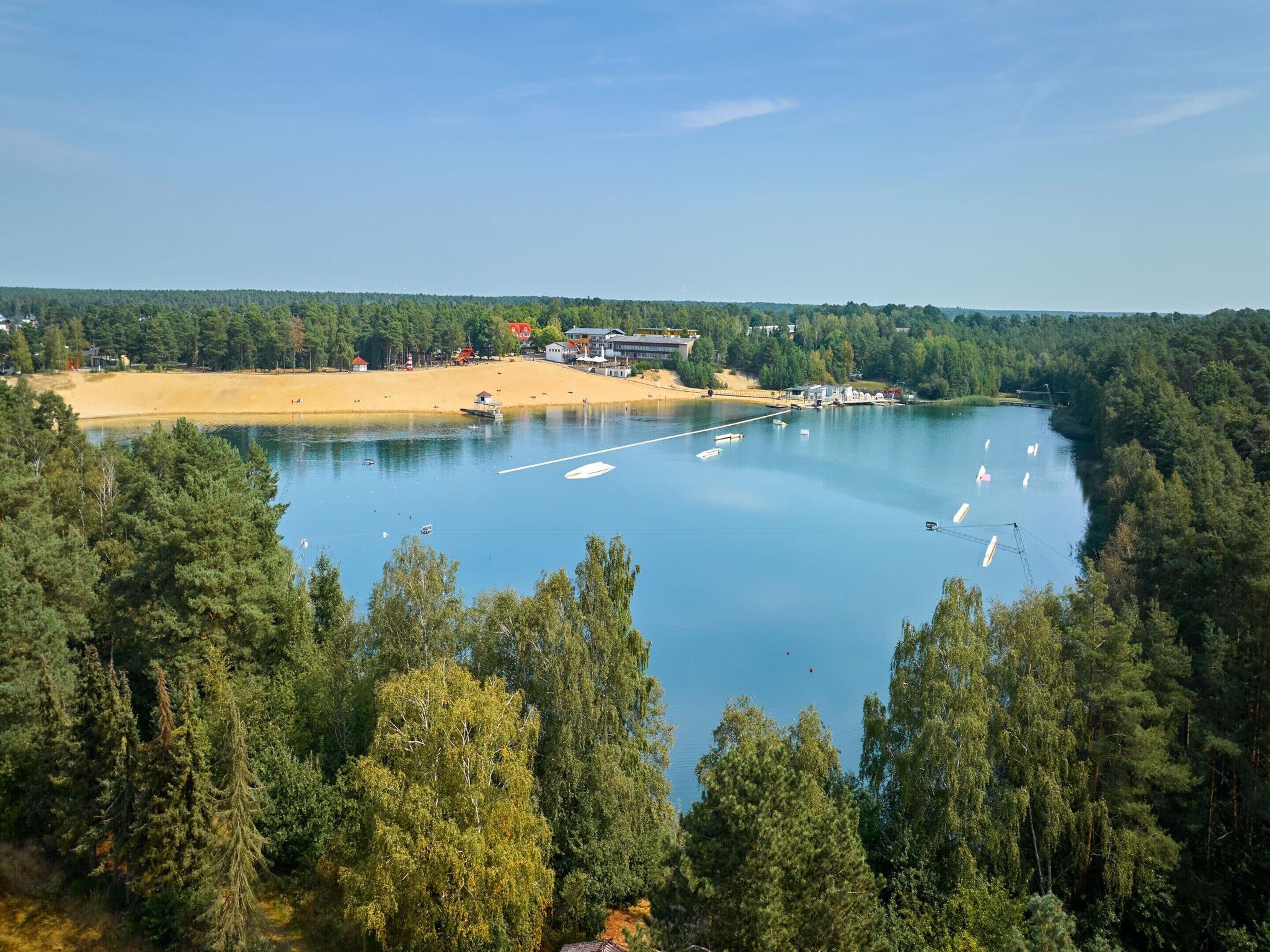 Un lago rodeado de un bosque denso con barcos anclados en el agua.