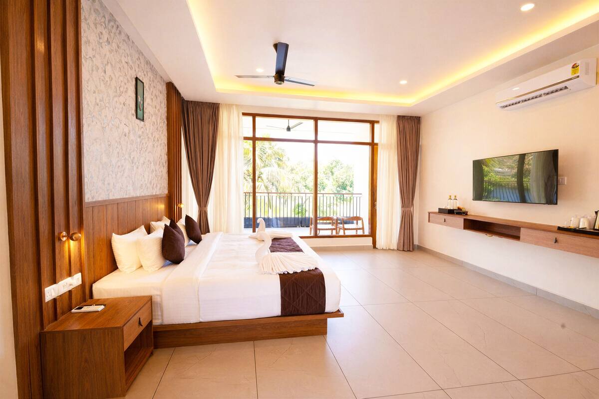 Hotelkamer met een groot bed, een televisie, een plafondventilator en een balkon met uitzicht.