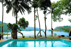 Una piscina al aire libre, sombrillas, sillones reclinables de piscina