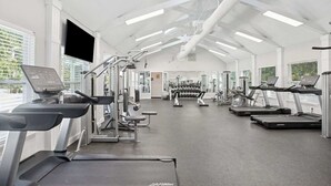 Ein Fitnessstudio mit Laufbändern, Kraftgeräten und Kurzhanteln.