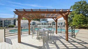 Ein überdachter Außenbereich mit Pool, Sitzgelegenheiten und Blick auf Wohnhäuser im Hintergrund.