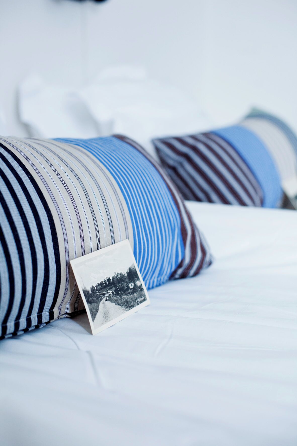 A bed with striped pillows and a photograph.