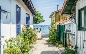 Uma viela estreita com edifícios em ambos os lados, que leva a um corpo d'água com barcos.