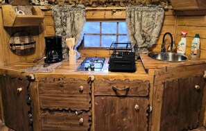 A rustic kitchen with a wooden countertop, a gas stove, a coffee maker, a sink, and a window with curtains. - 1 bedroom beautiful home in Rosporden (Rosporden)