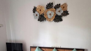 Un dormitorio con cama, televisor sobre un mueble bajo y una decoración en la pared.