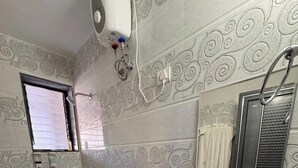 Un baño con inodoro, lavabo y espejo. Hay una ventana con persianas, un perchero y un dispensador de jabón en la encimera.