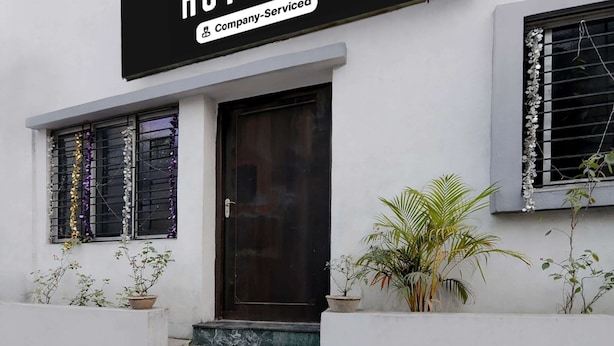 A building with a black sign above the door, potted plants, and a marble staircase leading to the entrance. - Classic The Orchid Residency (Kolkata)