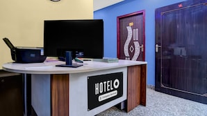 A hotel reception desk with a clock, a door with a number, and a sign indicating it's company-serviced. - Classic The Orchid Residency (Kolkata)
