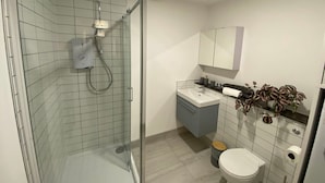 A modern bathroom with a glass shower enclosure, a vanity with a mirror, and a toilet. - Modern 2-Bed, Swindon Old Town (Swindon)