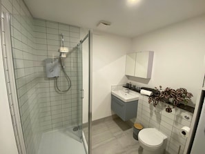 A modern bathroom with a glass shower enclosure, a vanity with a mirror, and a toilet. - Modern 2-Bed, Swindon Old Town (Swindon)