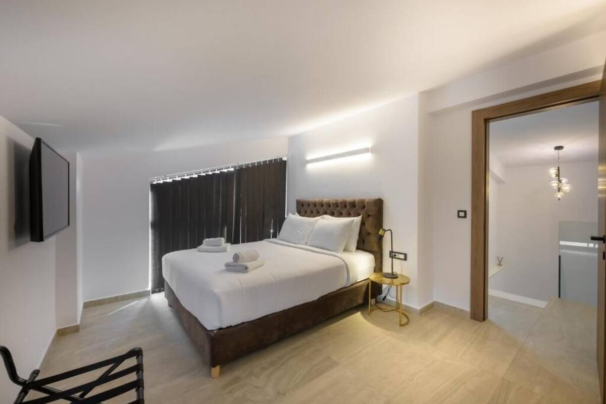 Een moderne hotelkamer met een groot bed, een nachtkastje, een aan de muur bevestigde televisie en een deur naar een badkamer.