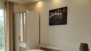 Ein modernes Schlafzimmer mit Bett, Nachttischen, einem Kleiderschrank und einem Gemälde an der Wand.