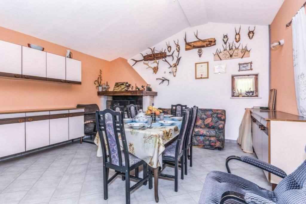 Ein Essbereich mit einem für vier Personen gedeckten Tisch, umgeben von Stühlen, einer Couch und einem Schrank mit Dekoration an der Wand.