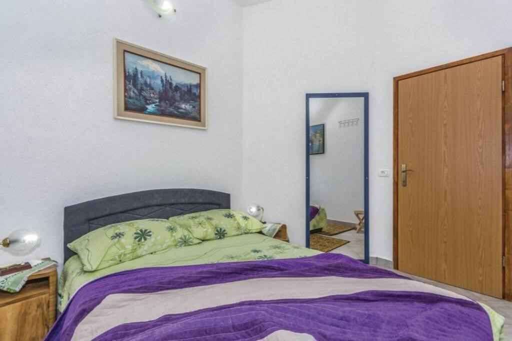Una camera da letto con un letto, un comodino, una cassettiera, uno specchio e una porta.