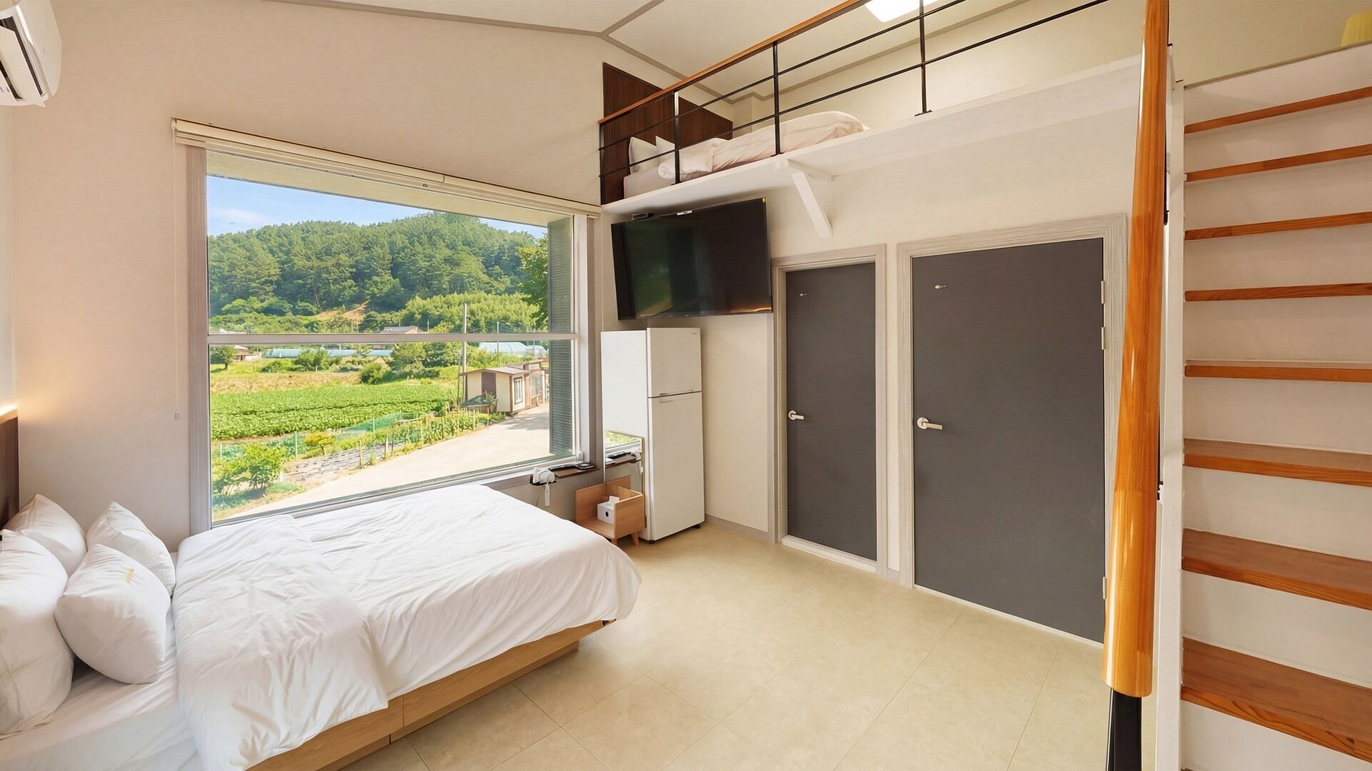 Une chambre avec un lit, une télévision, une armoire et une vue sur un vignoble.