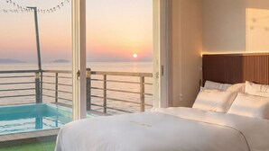 A hotel room with a bed, a view of the sea, and a balcony with a pool. - Taean Solpleo Pool Villa (Taean)