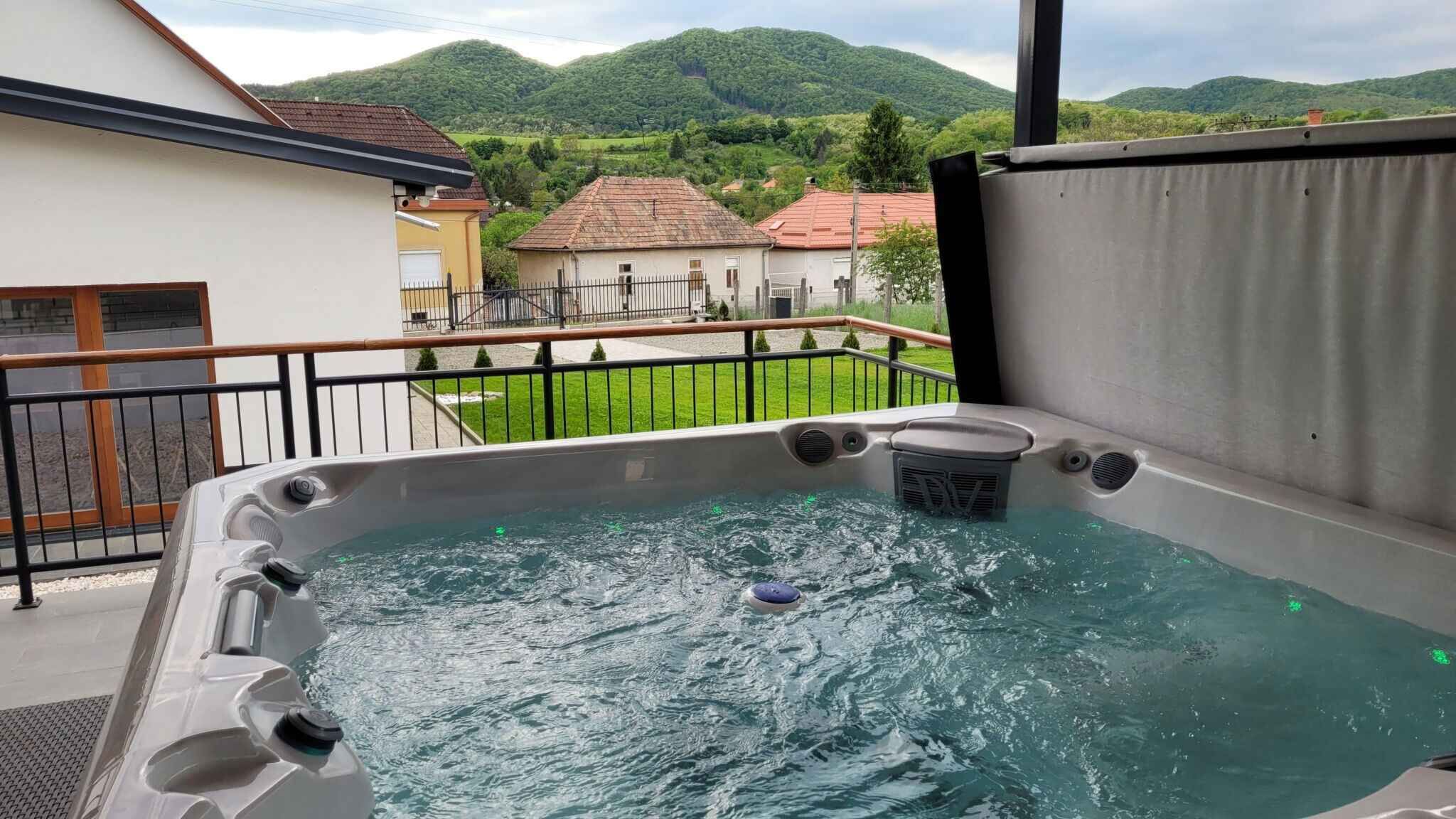 Un jacuzzi en un balcón con vistas a un paisaje verde y casas.
