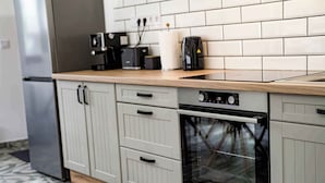 Een keuken met een roestvrijstalen koelkast, een inbouwoven en een koffiezetapparaat op het aanrecht.