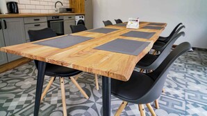 Een houten vergaderruimte met zwarte stoelen, een koffieapparaat en een keuken op de achtergrond.