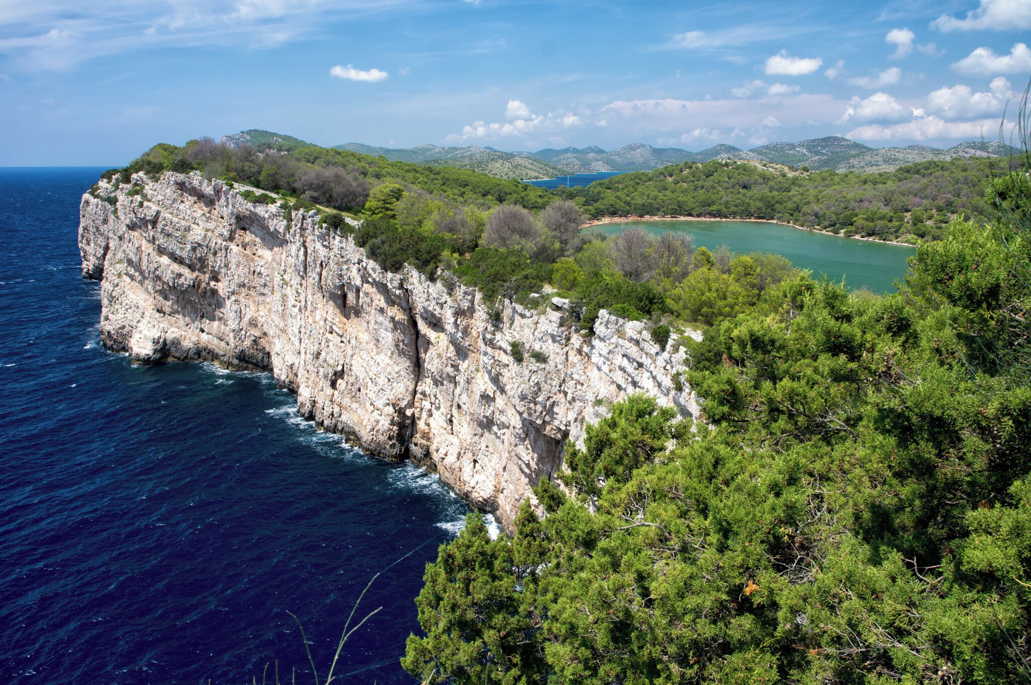 Acantilado costero con vista al mar y un paisaje verde distante.