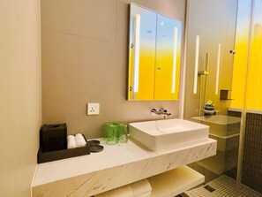 A modern bathroom with a white sink, a mirror, and a glass shower enclosure. - Wink Hotel Can Tho (CAN THO)