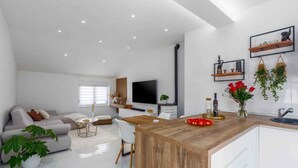 A modern kitchen with a wooden island, white cabinetry, and a built-in TV. - Holiday apartment with air conditioning and balcony (Funtana)