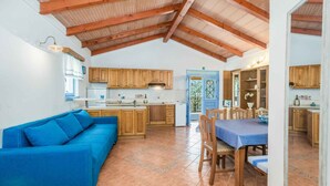 Eine geräumige Küche mit Holzausstattung, einem Essbereich mit blauem Tisch und einem blauen Sofa.