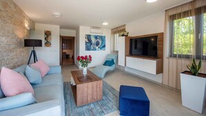 A modern living room with a sofa, coffee table, and TV. - Holiday apartment with shared-use pool (Sv. Filip i Jakov)