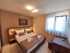 A hotel room with a large bed, bedside tables, a desk, and a chair. - Holiday apartment with pool and air conditioning (Sv. Filip i Jakov)