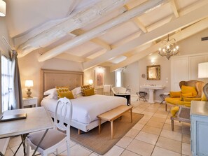 A spacious bedroom with a large bed, a sitting area with a sofa and armchair, a vanity with a mirror, and a chandelier. - Château De Mazan - Handwritten Collection (Mazan)