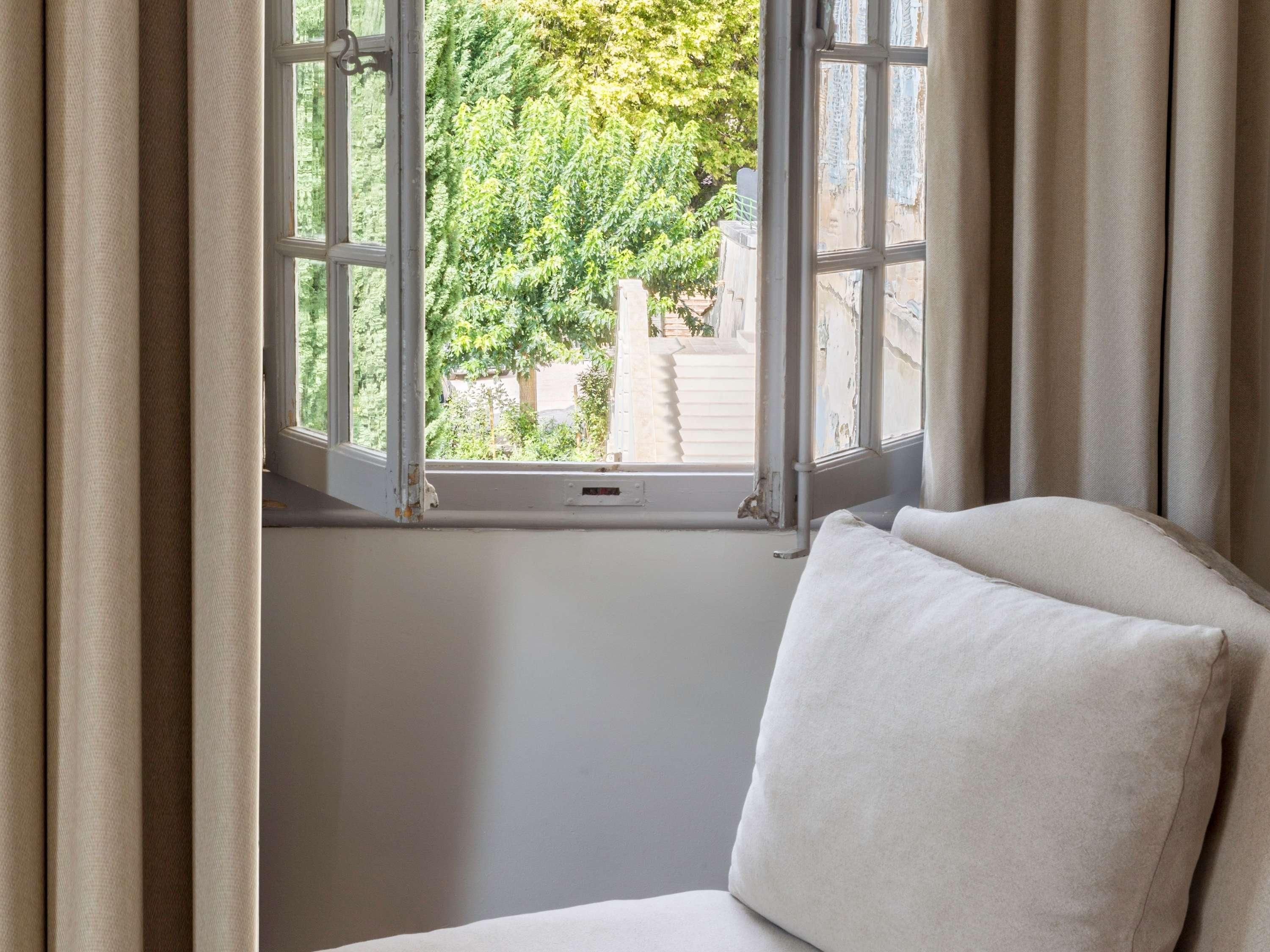 Una habitación con ventana, una silla blanca y vistas a la vegetación.