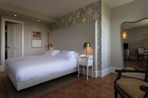 A neatly arranged bedroom with a bed, bedside tables, a chair, and a mirror. - Château De Mazan - Handwritten Collection (Mazan)