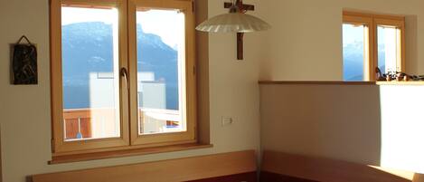 Ein Essbereich mit einem Holztisch und Stühlen, einer Bank und Bergblick durch große Fenster.