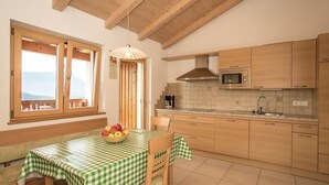A kitchen with wooden cabinets, a microwave, a stove, and a window with a view. - Apartment 'Pföslhof Weinberg' with Mountain View, Shared Garden and Wi-Fi (Leifers)