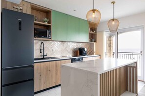 A modern kitchen with a black refrigerator, wooden cabinets, a microwave, and a large island. - Holiday home with pool and sea view (Blato/Insel Korčula)