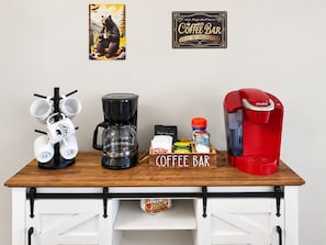 Ein Kaffee-Bereich mit einer Kaffeemaschine, Tassen und Kaffeezubehör auf einer Holztischplatte.