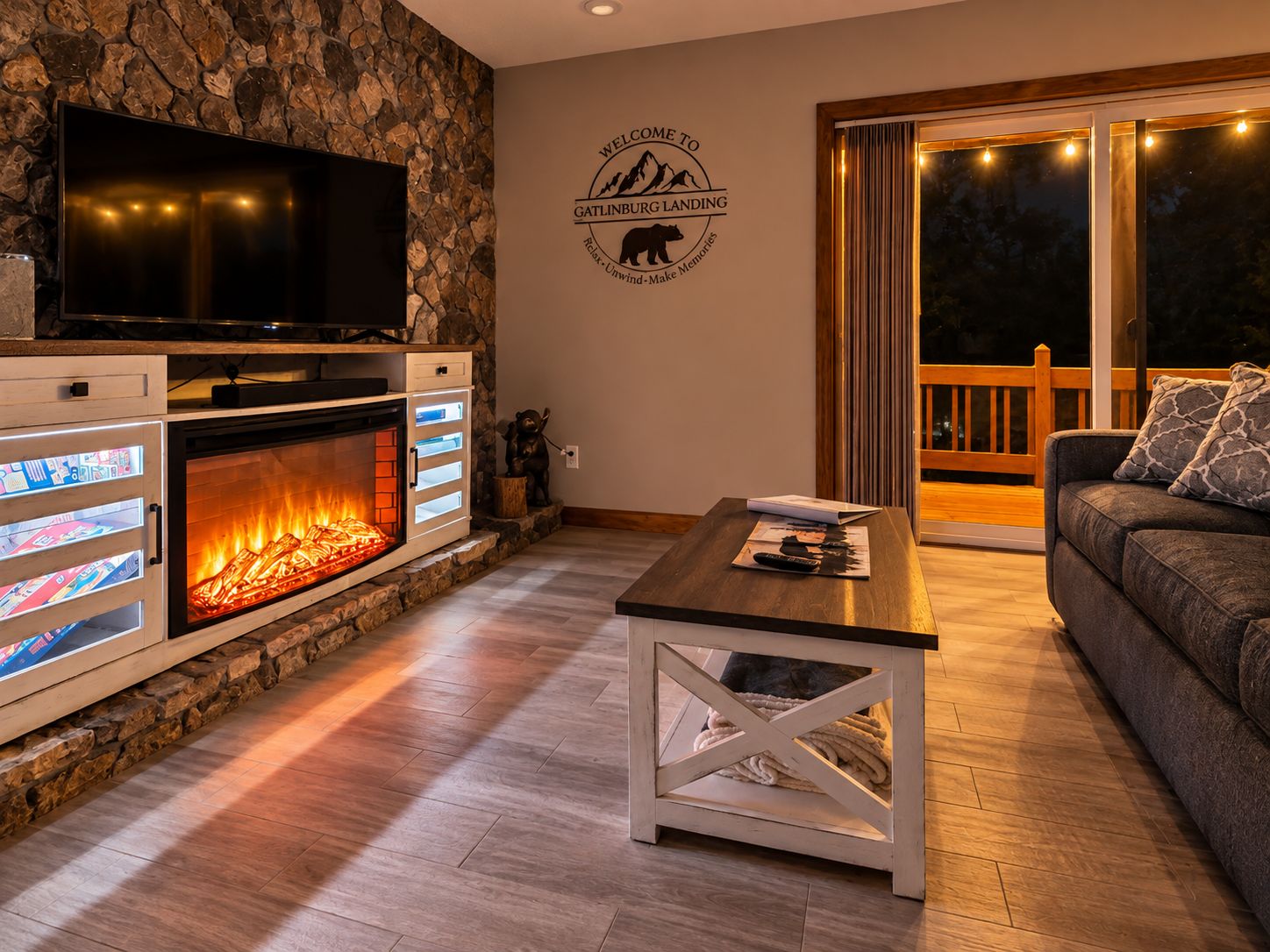 A cozy living room with a stone wall, a fireplace, a television, and a sofa.