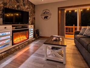 Ein gemütliches Wohnzimmer mit Steinwand, Kamin, Fernseher und einer Couch.