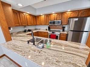 Una cucina moderna con mobili in legno, elettrodomestici in acciaio inossidabile, un piano di lavoro in granito e un forno a microonde integrato.