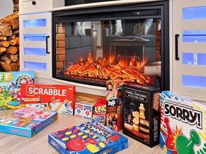 Una sala de estar acogedora con chimenea, varios juegos de mesa y un televisor.