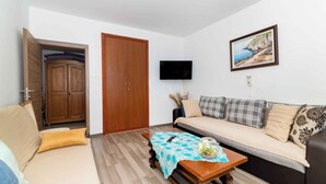 Ein Wohnzimmer mit einer Couch, einem Holzschrank, einem Fernseher und einem Gemälde an der Wand.