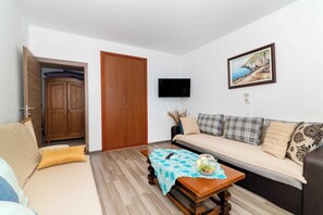 Una sala de estar con sofá, un aparador de madera, televisor y un cuadro en la pared.