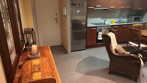 Una cocina moderna con electrodomésticos de acero inoxidable, un comedor con mobiliario de mimbre y una barra de madera.