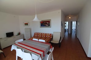 Ein Schlafzimmer mit einem Bett, einem Schreibtisch mit Fernseher, einem Sessel und einem Tisch.