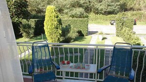 Un balcone con due sedie blu e un tavolino con oggetti sopra.