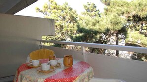 A balcony with a table set for tea, overlooking trees. - Holiday apartment mit Balkon (Lignano Sabbiadoro)