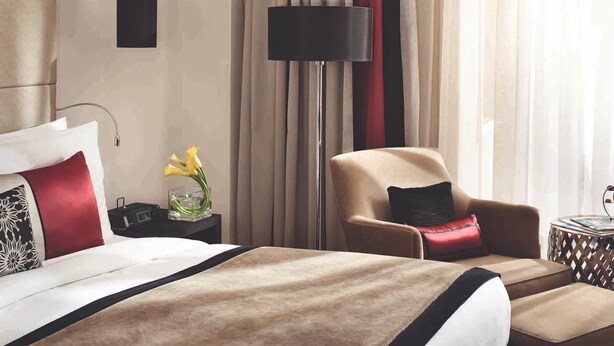 Une chambre d’hôtel avec un lit, une chaise, une lampe et des rideaux.